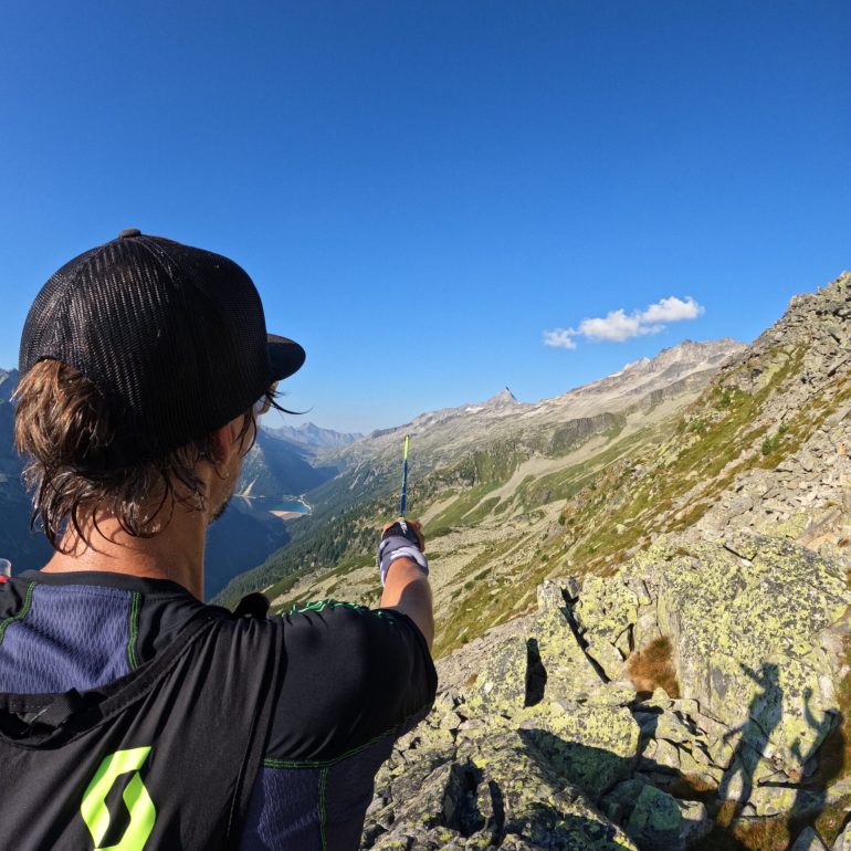 Trainer Martin Kaschmann zeigt mit dem Trailrunningstock Richtung Horizont